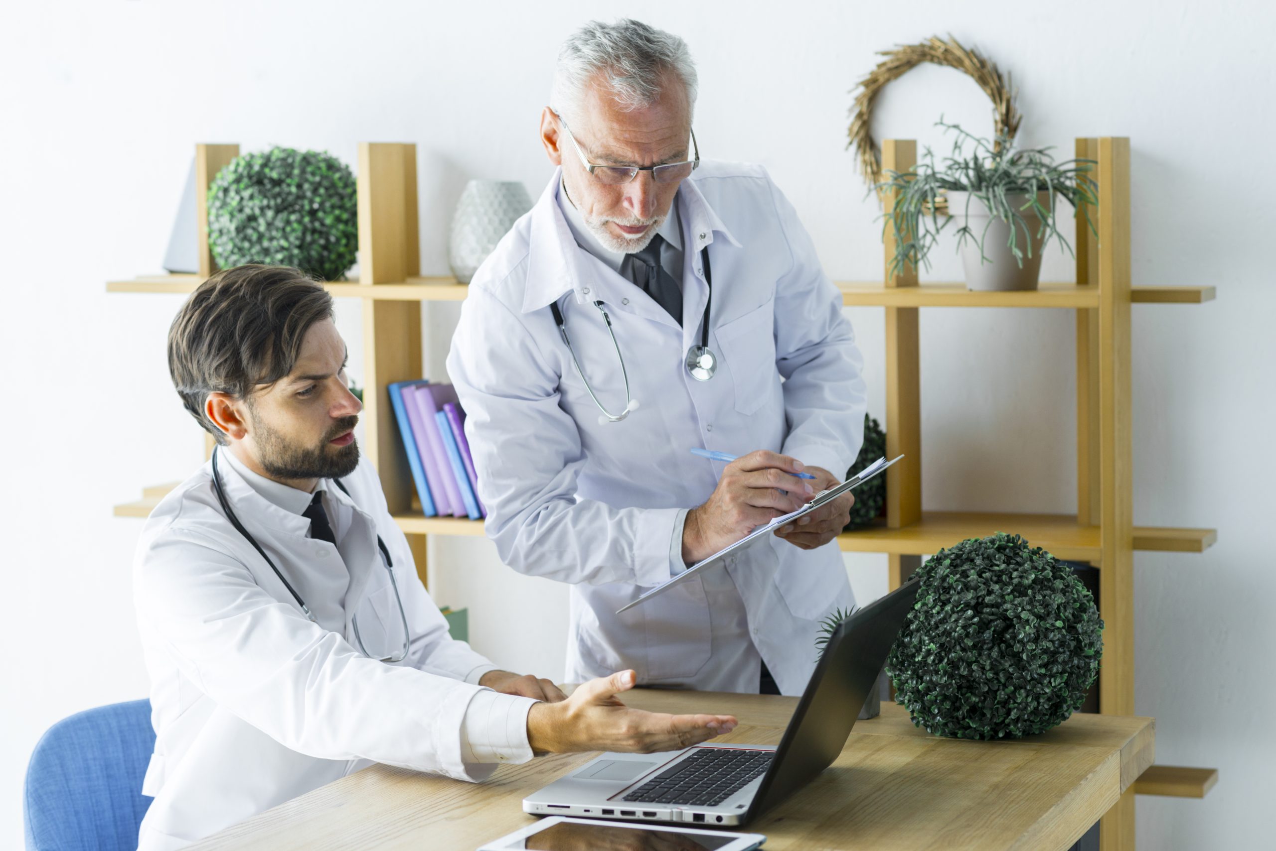 elderly doctor making notes while helping colleague