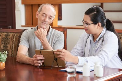 woman showing tablet to elderly patient