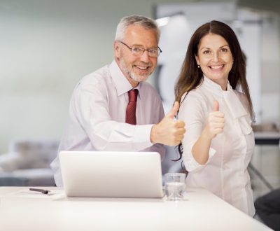 portrait smiling senior businessman businesswoman showing thumb up sign office