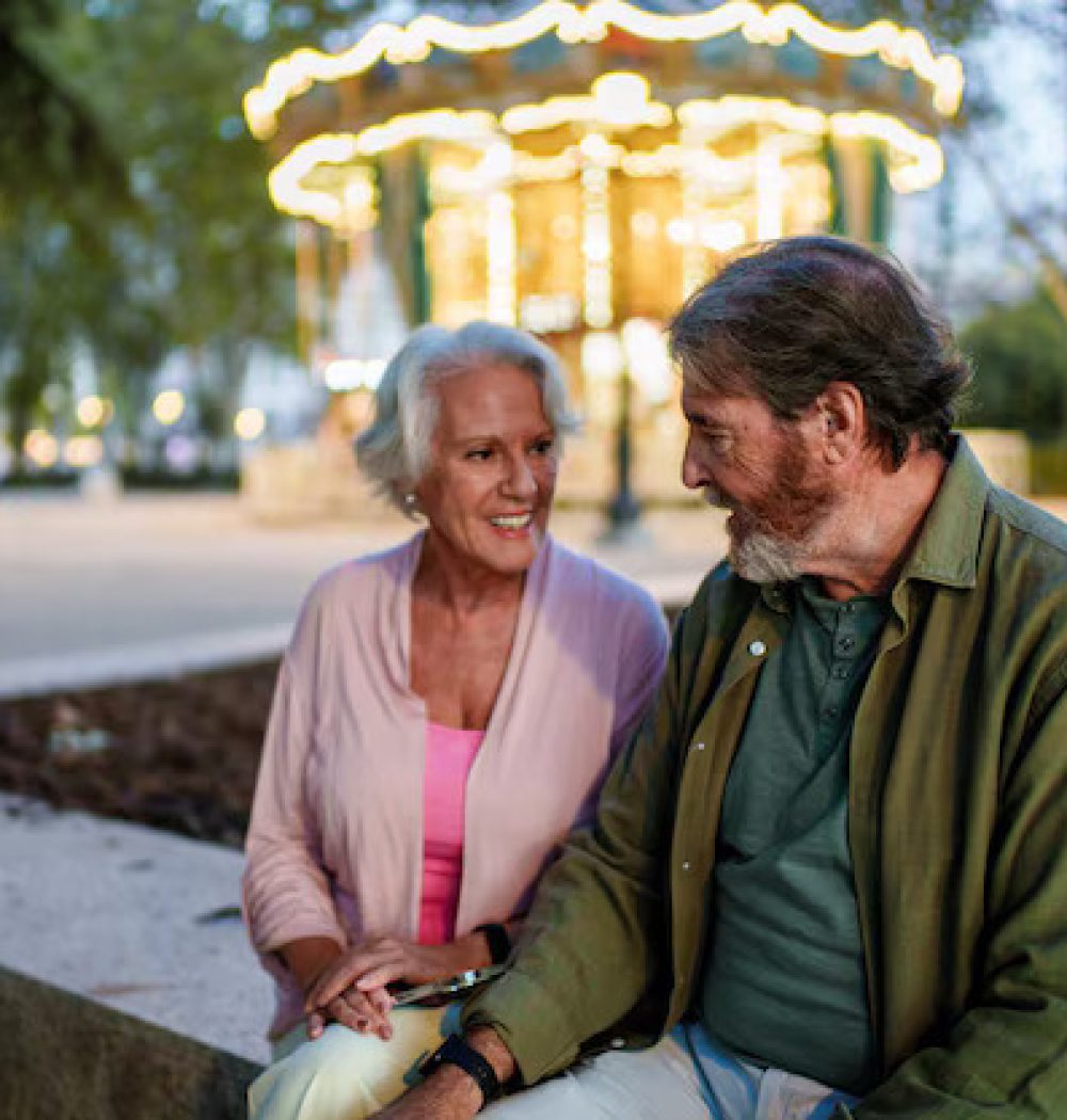 senior-couple-holding-hands-talking-near-carousel-dusk_198115-5822